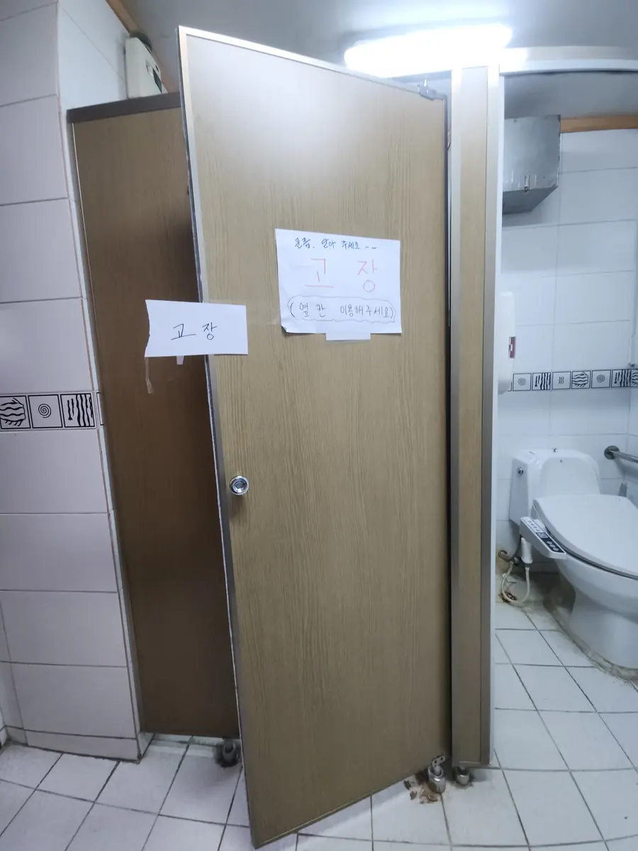 빌딩화장실큐비클 빌딩상가화장실 큐비클 문짝이 떨어져 고장 표시가 붙은 수리 전 상태
